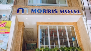 El exterior del Morris Hotel, con un letrero llamativo, un ventanal grande y un techo decorativo.