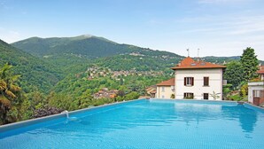 A swimming pool with a view of a mountainous landscape and a building with a red roof. - Villa "Luxury Oleandra" with Private Pool, Big Garden and Barbecue (Dizzasco)