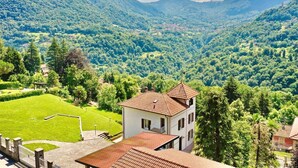 A building with a red-tiled roof, surrounded by lush green trees and a valley. - Villa "Luxury Oleandra" with Private Pool, Big Garden and Barbecue (Dizzasco)
