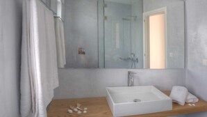 Un baño con un espejo grande, un lavamanos blanco y una cabina de ducha de vidrio.