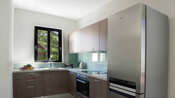 Una cocina moderna con armarios de madera, un refrigerador de acero inoxidable, un horno empotrado y una ventana con vistas a zonas verdes.