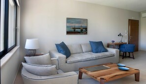 A living room with a sofa, a coffee table, a lamp, and a painting on the wall.