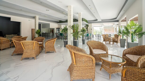 A spacious lobby with wicker furniture, a marble floor, and large windows.