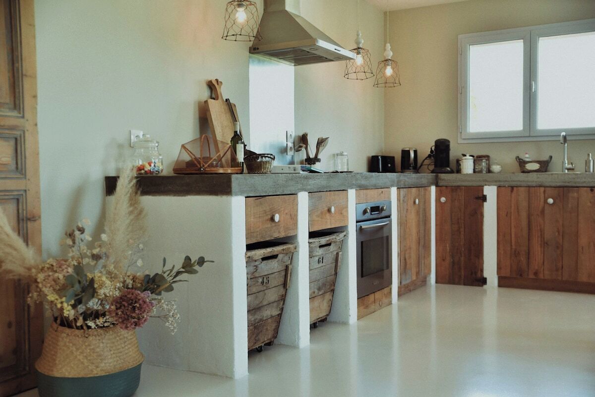 Una cocina con armarios de madera, horno empotrado y un ventanal grande.
