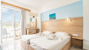 Een hotelkamer met twee bedden, een badkamer, een balkon en uitzicht op het landschap.