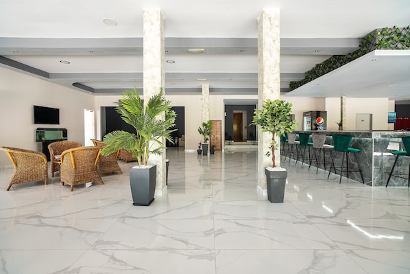 A lobby with a reception desk, seating area, and potted plants.