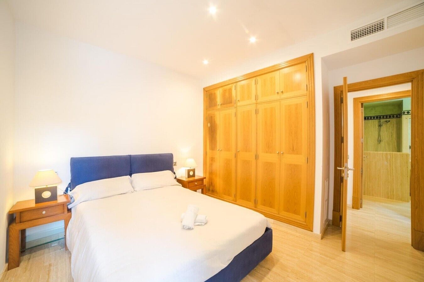 A bedroom with a bed, bedside tables, a wardrobe, and a bathroom door.