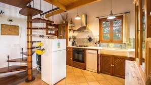 A kitchen with wooden cabinets, a white refrigerator, a stove, and a window with curtains.