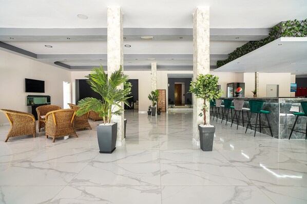 A lobby with a reception desk, seating area, and potted plants.