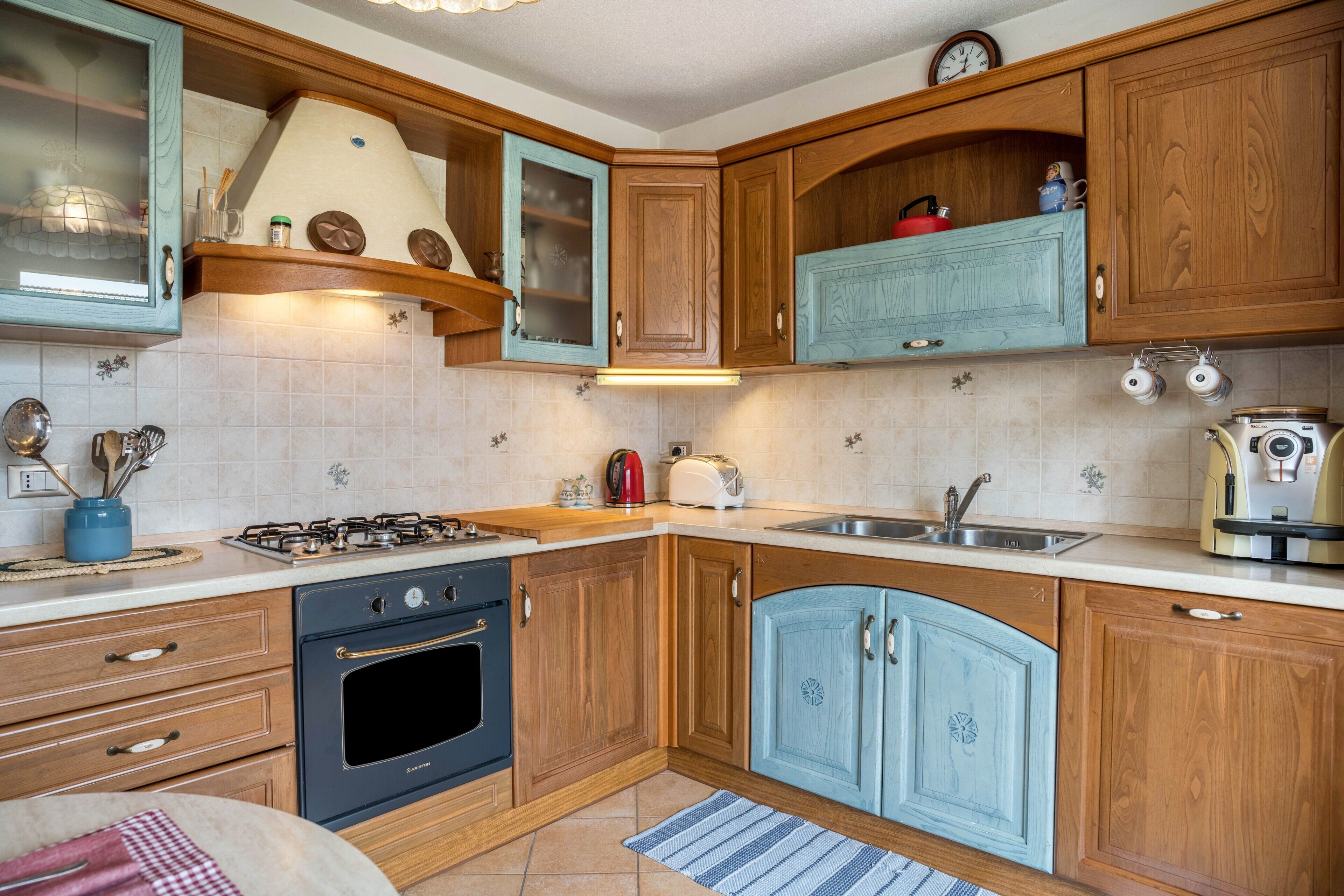Een keuken met houten kastjes, een fornuis, een spoelbak en een broodrooster.