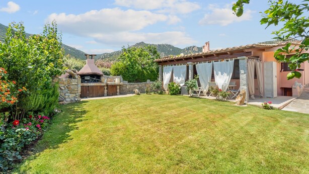 Un jardin bien entretenu, agrémenté d’un mur en pierre, d’une pergola en bois et d’une cheminée en pierre.