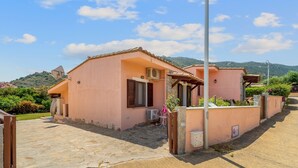 Un bâtiment rose avec un patio en pierre, un climatiseur et un portail.