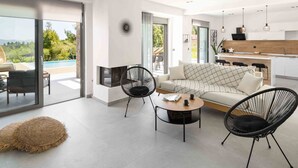 A modern living room with a sofa, two chairs, a coffee table, and a fireplace. - K-Koni Villa, Agia Paraskevi by Halkidiki Villas (Pallini)