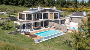 A modern two-story house with a swimming pool, stone walls, and a car parked nearby. - K-Koni Villa, Agia Paraskevi by Halkidiki Villas (Pallini)