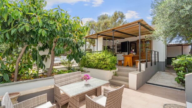 An outdoor patio with wicker furniture, a table with a vase of flowers, and a covered area with a bench. - Holiday Home 'Villa Matteo' with Sea View, Wi-Fi and Air Conditioning (Perd'e Sali CA)