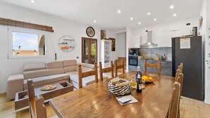 A modern kitchen with a dining area, wooden furniture, and a view through a window. - Holiday Home 'Villa Matteo' with Sea View, Wi-Fi and Air Conditioning (Perd'e Sali CA)