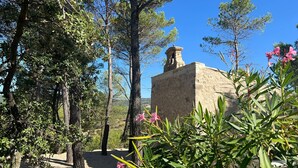 A stone structure with a bell tower, surrounded by trees and greenery.