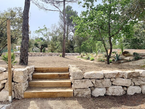 A stone staircase leading up to a wooden platform surrounded by a garden with various plants and trees. - exceptional view villa (Murs)