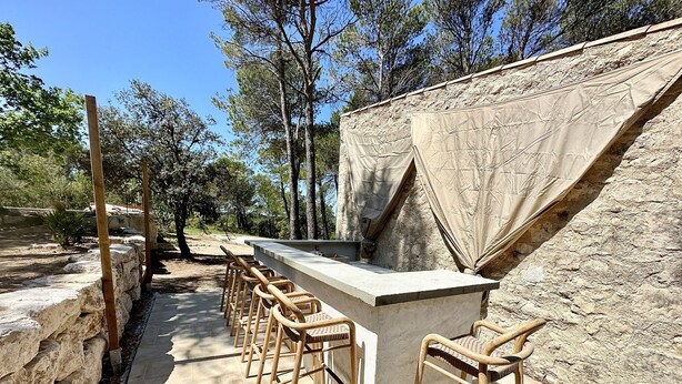 An outdoor bar area with stone seating and a concrete counter.