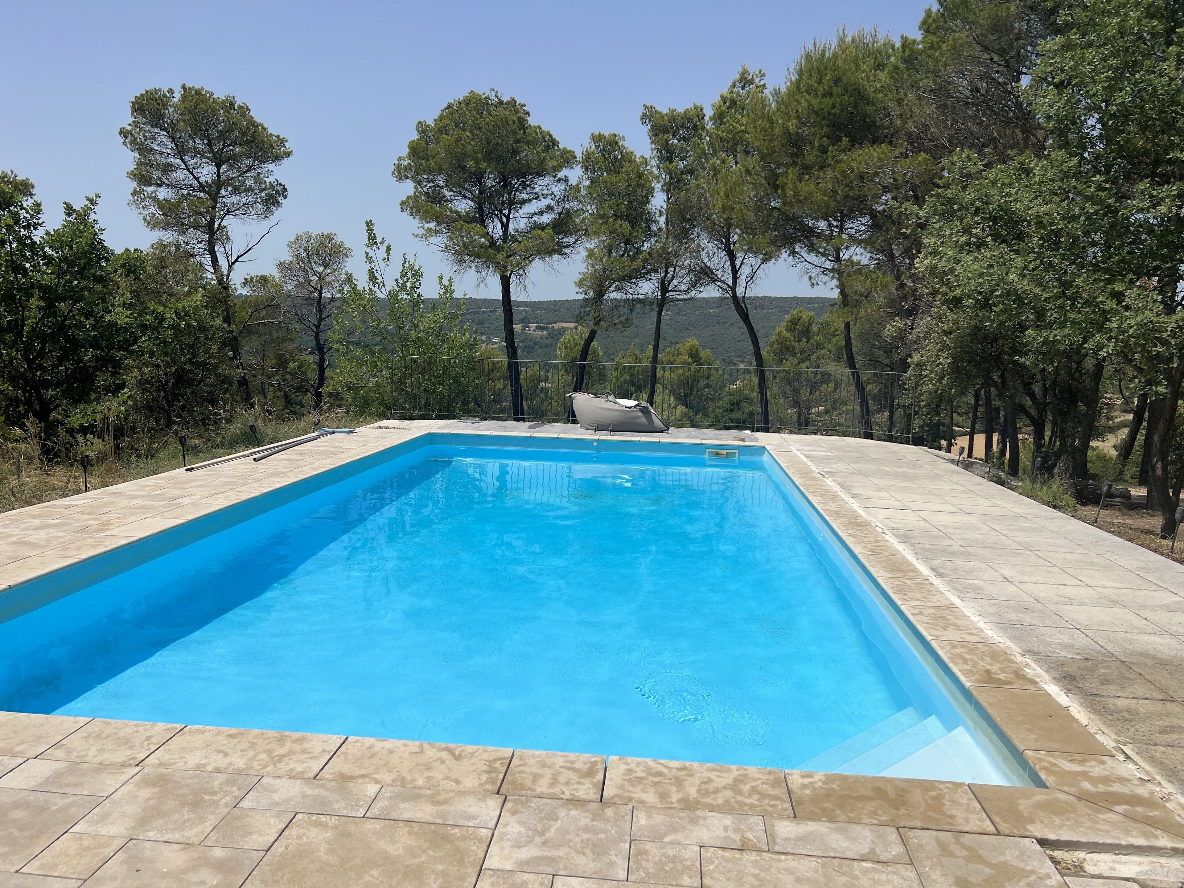 A rectangular swimming pool with clear blue water, surrounded by a tiled deck.