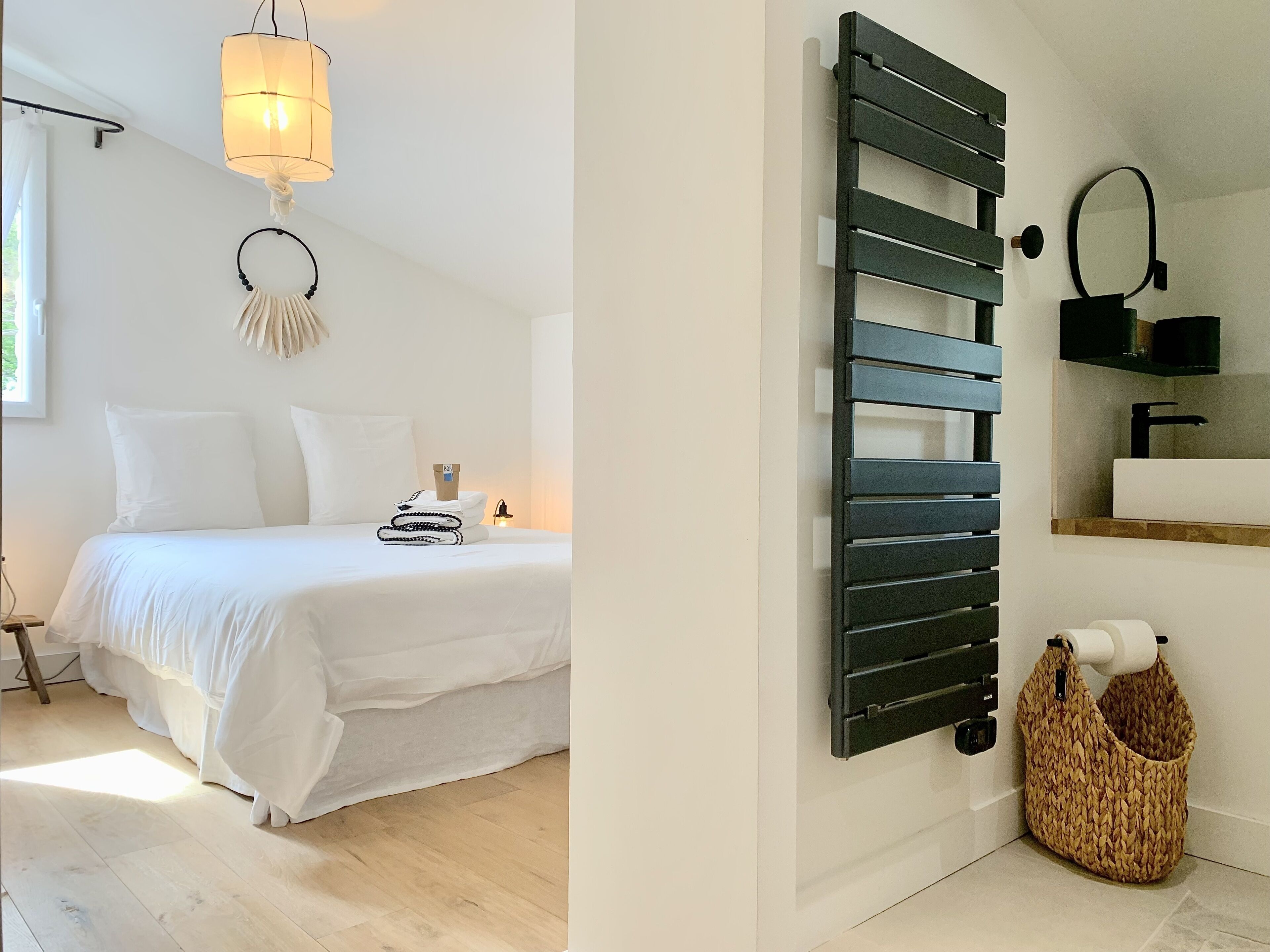 A modern bedroom with a bed, bedside table, lamp, and a wall-mounted radiator.