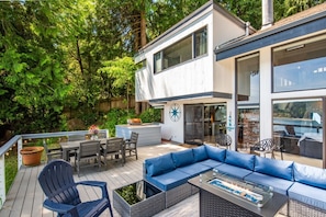 A modern house with a deck, outdoor seating, and a fire pit.