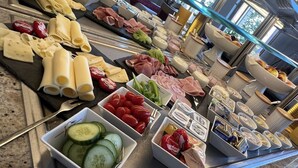 Een buffet met diverse kazen, vleeswaren en groenten.