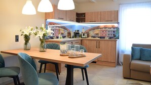 A modern kitchen with wooden cabinets, a dining table with chairs, and pendant lights. - 3 Raum Appartement Hotel Garni am Domplatz (ERfurt)