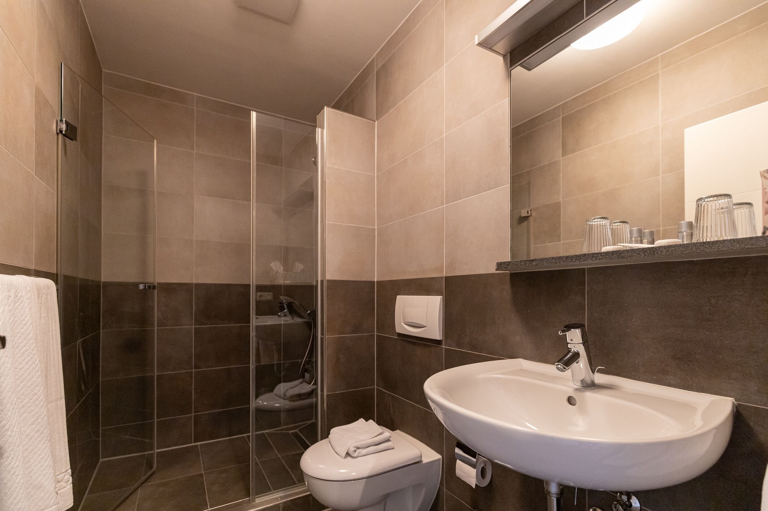 Ein modernes Badezimmer mit einer Duschkabine, einem weißen Waschbecken und einer Toilette.