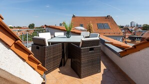 A rooftop terrace with a table and chairs, a potted plant, and a view of the cityscape. - Penthouse Hotel Garni am Domplatz (Erfurt)