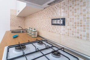 Een koelkast, een oven, een kookplaat, kookgerei, borden en bestek