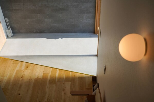 Een moderne kamer met een houten vloer, een grijze muur en een klein raam.