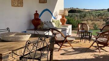 Un patio al aire libre con mobiliario de mimbre, una mesa con una cesta tejida y jarrones decorativos.