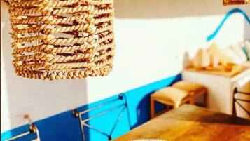 Un comedor con una mesa de madera, lámparas colgantes de mimbre y una pared azul de acento.