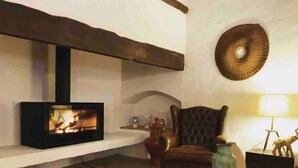A fireplace with a modern design, a wooden chair, and a decorative wall piece.