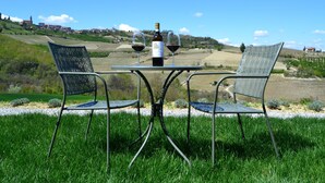 Deux chaises en métal, une table entre elles, une bouteille de vin et deux verres à vin sur la table.