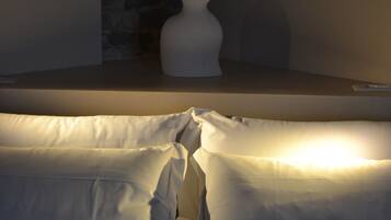 Een bed met wit beddengoed en een witte vaas op een nachtkastje.