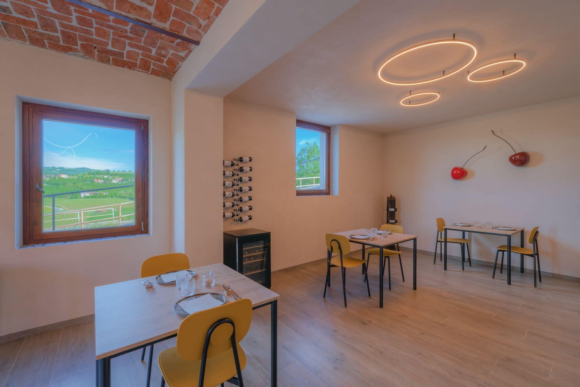 Un comedor con pared de ladrillo, ventanas amplias y una estantería para vinos.
