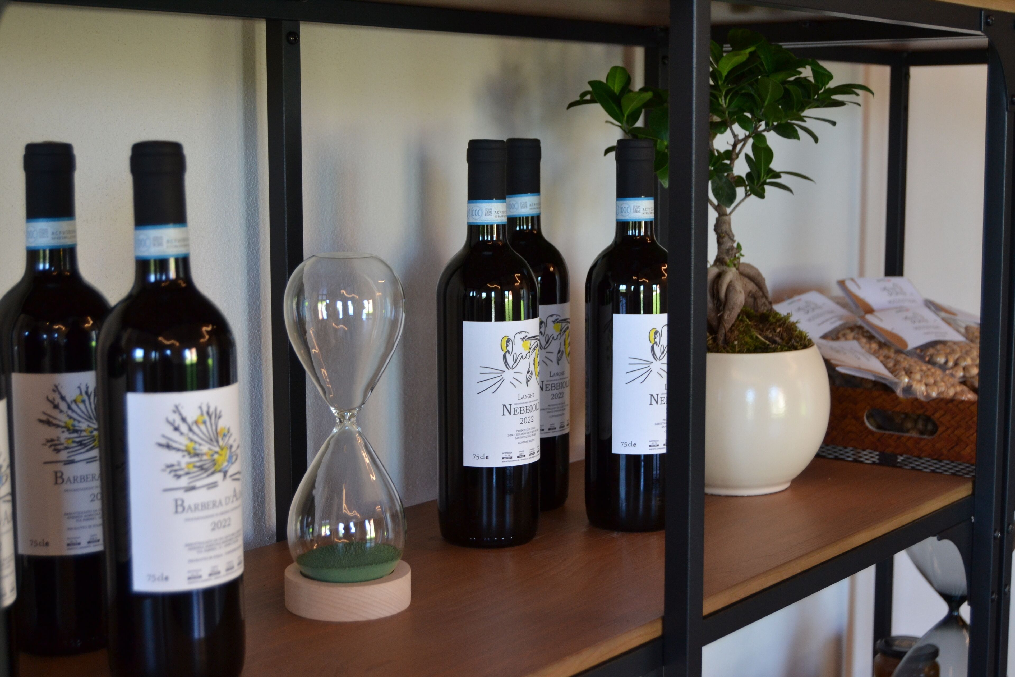 A shelf with wine bottles, an hourglass, and a potted plant.
