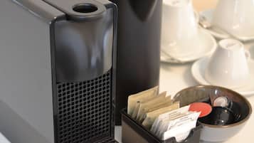 Een zwarte speaker, een zwarte container met papieren en een kom met een lepel op een tafel.