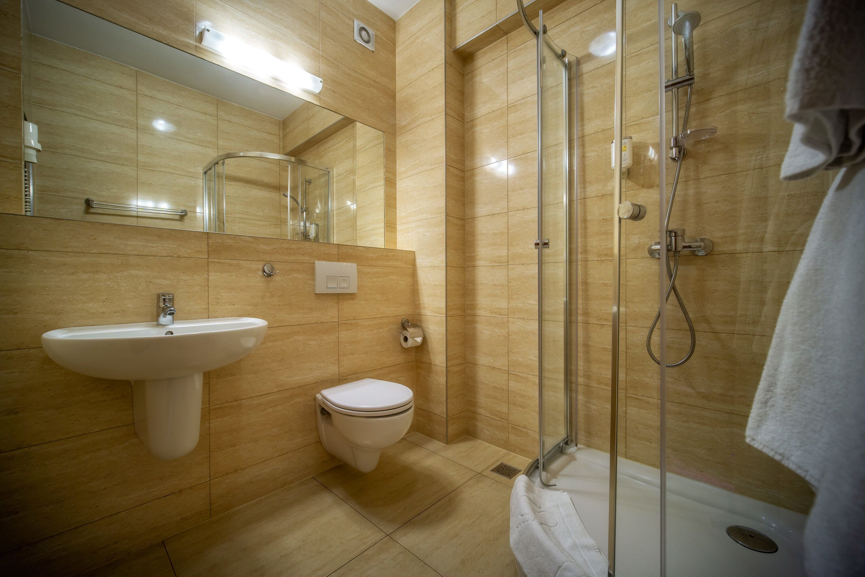 Un baño moderno con lavamanos, inodoro y ducha con mampara de vidrio.
