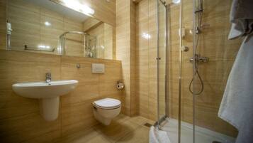 Un baño moderno con lavamanos, inodoro y ducha con mampara de vidrio.