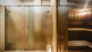 Una sala de sauna con puertas de vidrio, bancos de madera y techo de madera.