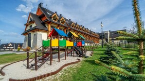 Una hilera de estructuras de juego coloridas en un parque, con un edificio al fondo.