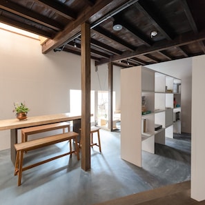 Un intérieur moderne avec des poutres apparentes, un banc en bois et une étagère blanche.