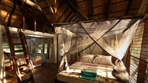 A room with a bed under a mosquito net, a wooden ladder, and a window with blinds. - Zikomo Safari Lodge (South Luangwa National Park)