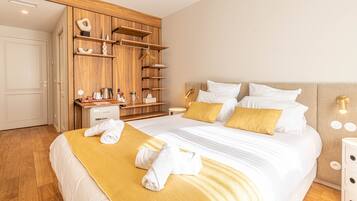 Une chambre d’hôtel avec un grand lit, une armoire en bois, des tables de chevet et une petite table de nuit.