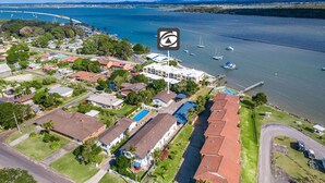 An aerial view of a coastal residential area with houses, a swimming pool, and a marina with boats. - Iluka Villa 10 right on the Clarence River (ILUKA)