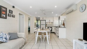 A modern kitchen with white cabinets, a dining table with chairs, and a ceiling fan. - Iluka Villa 10 right on the Clarence River (ILUKA)