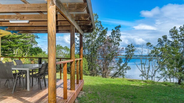 A wooden deck with outdoor furniture overlooking a body of water. - Serenity Now Great Location (Iluka)